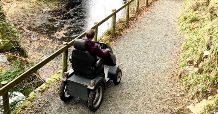 man sat in a tramper mobility scooter as he follows the footpath down to High Force Waterfall.